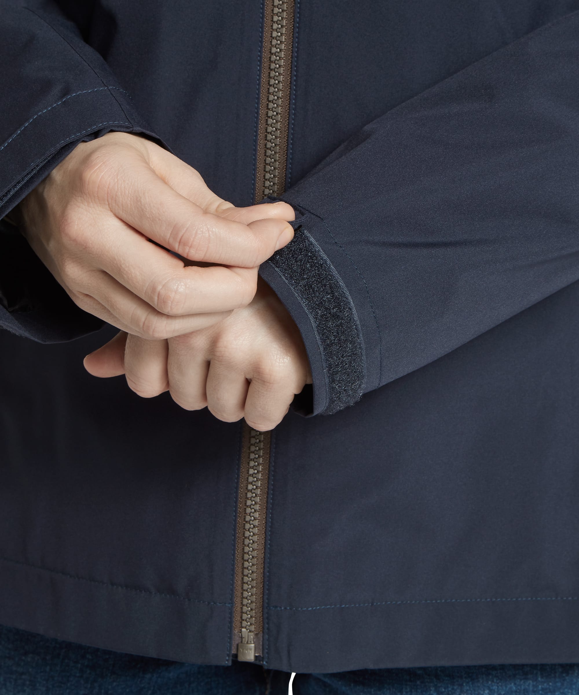 Close-up detail of the cuff on the Women's Schöffel Manton Lightweight Waterproof Jacket in midnight navy, showing the velcro adjustable cuff tab, inner gaiter sleeve and antique brass full-length zip for a secure, weatherproof fit.