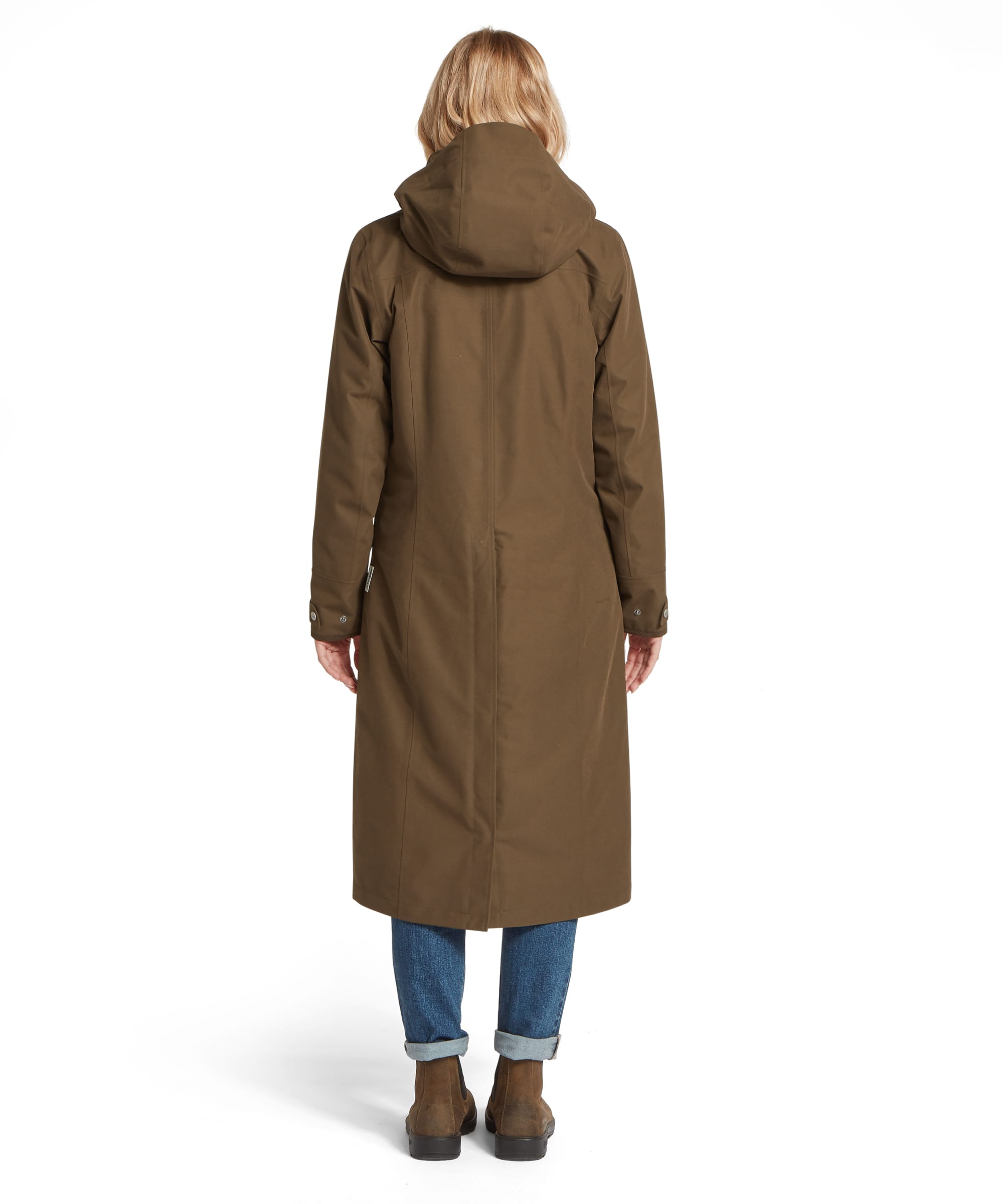 Back view of the Schöffel Women's Marefield Waterproof Coat in Dark Olive, showing the clean back seam construction, structured hood, snap-fastened cuffs and elegant full-length silhouette, worn with turn-up blue jeans and suede Chelsea boots