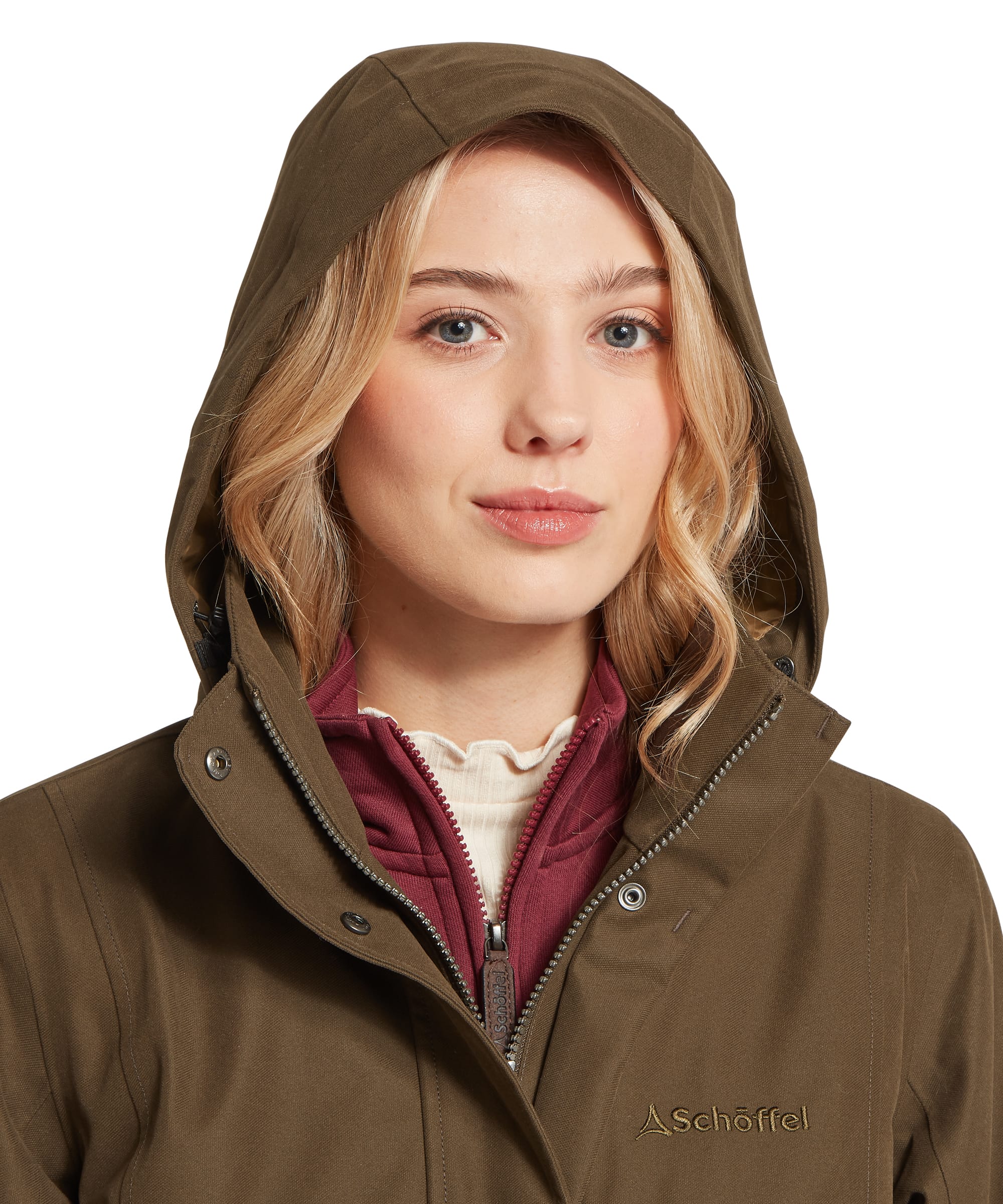 Schöffel Women's Marefield Waterproof Coat in khaki green, close-up of the structured hood with drawcord adjustment, showing the Schöffel embroidered logo and snap-tab placket collar, with a burgundy fleece and cream roll-neck visible beneath
