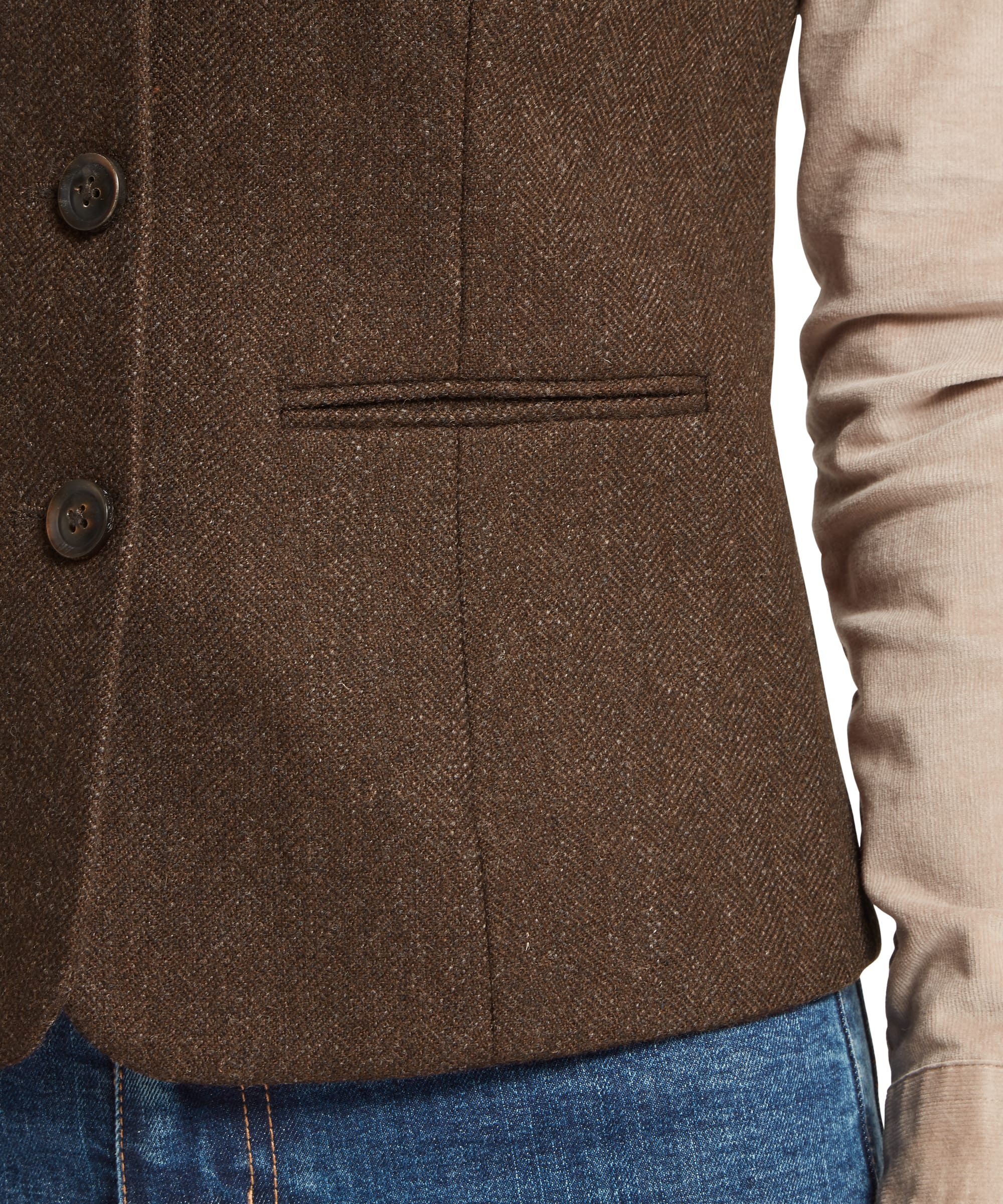 Close-up of the button fastening and welt pocket detail on the Schöffel Women's Millport Tweed Nehru Waistcoat in Brown Herringbone, highlighting the dark horn buttons and rich herringbone tweed weave, layered over a stone knitwear