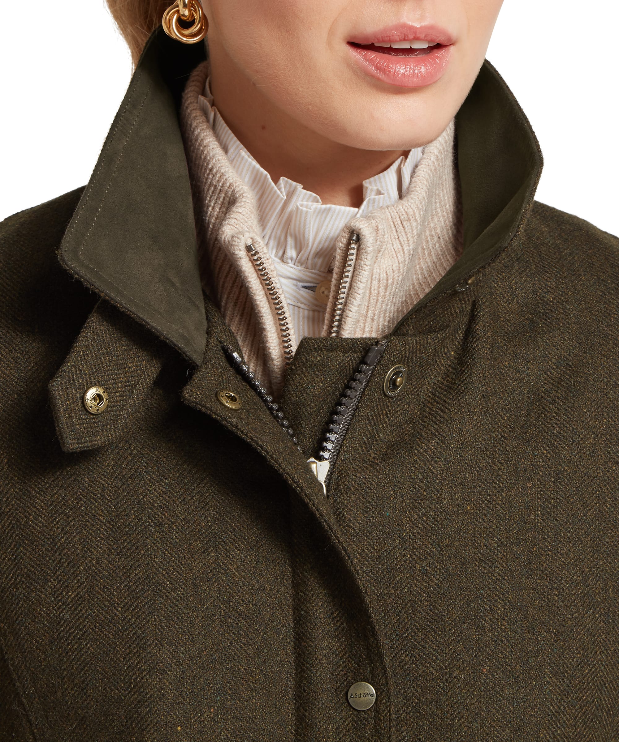 Close-up collar detail of the Schöffel Women's Murra Tweed Coat in olive herringbone tweed, showing the suede-trimmed stand collar, gold snap buttons with Schöffel branding, central zip opening, and layered styling with a chunky knit zip-neck and ruffle-collar shirt beneath