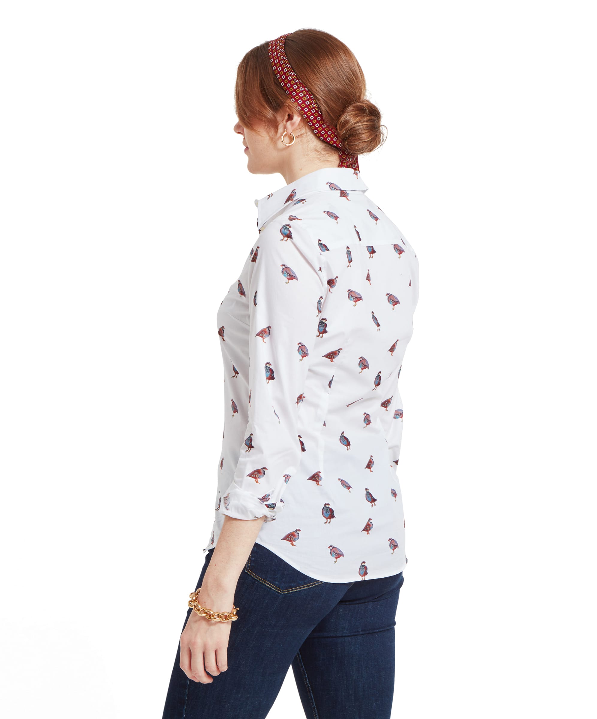 A rear view of a woman wearing a Schöffel Norfolk Shirt for Womens in Brown White with a partridge bird pattern. Her hair is tied in a low bun with a red headband, and she is wearing dark blue jeans.