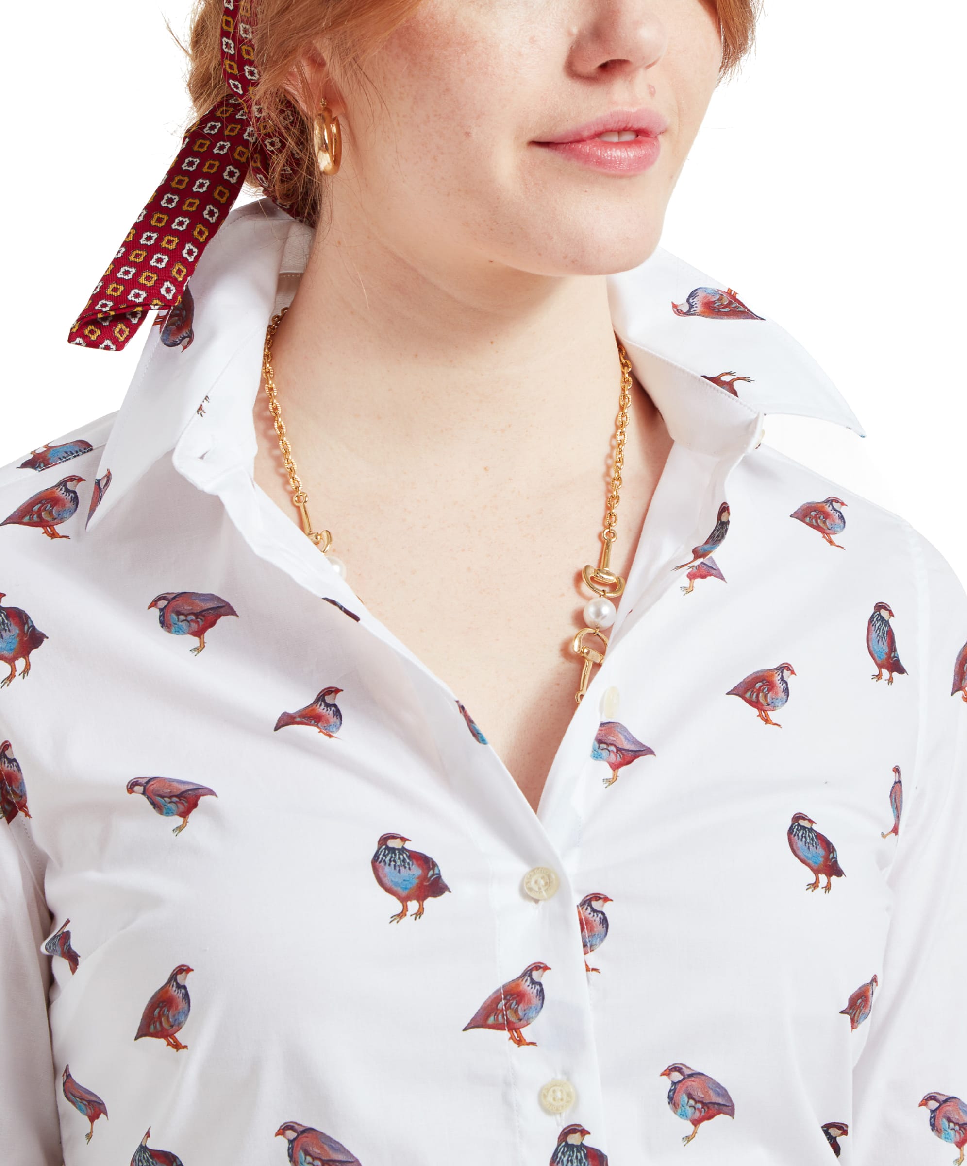 A close-up of a woman's chest and neck area, showing a Schöffel Norfolk Shirt for Womens in Brown White with a partridge bird pattern, a gold chain necklace with a pearl pendant, and a red headband. The shirt collar is slightly popped up.