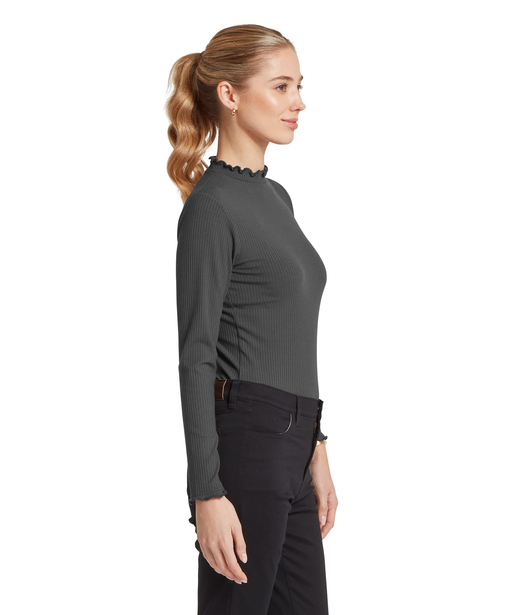 Side view of the Women's Schöffel Roseberry Top in charcoal grey ribbed jersey, showing the slim-fitting profile with the delicate frill-edged mock neck and matching frilled cuffs, styled with a brown leather belt and slim black trousers.