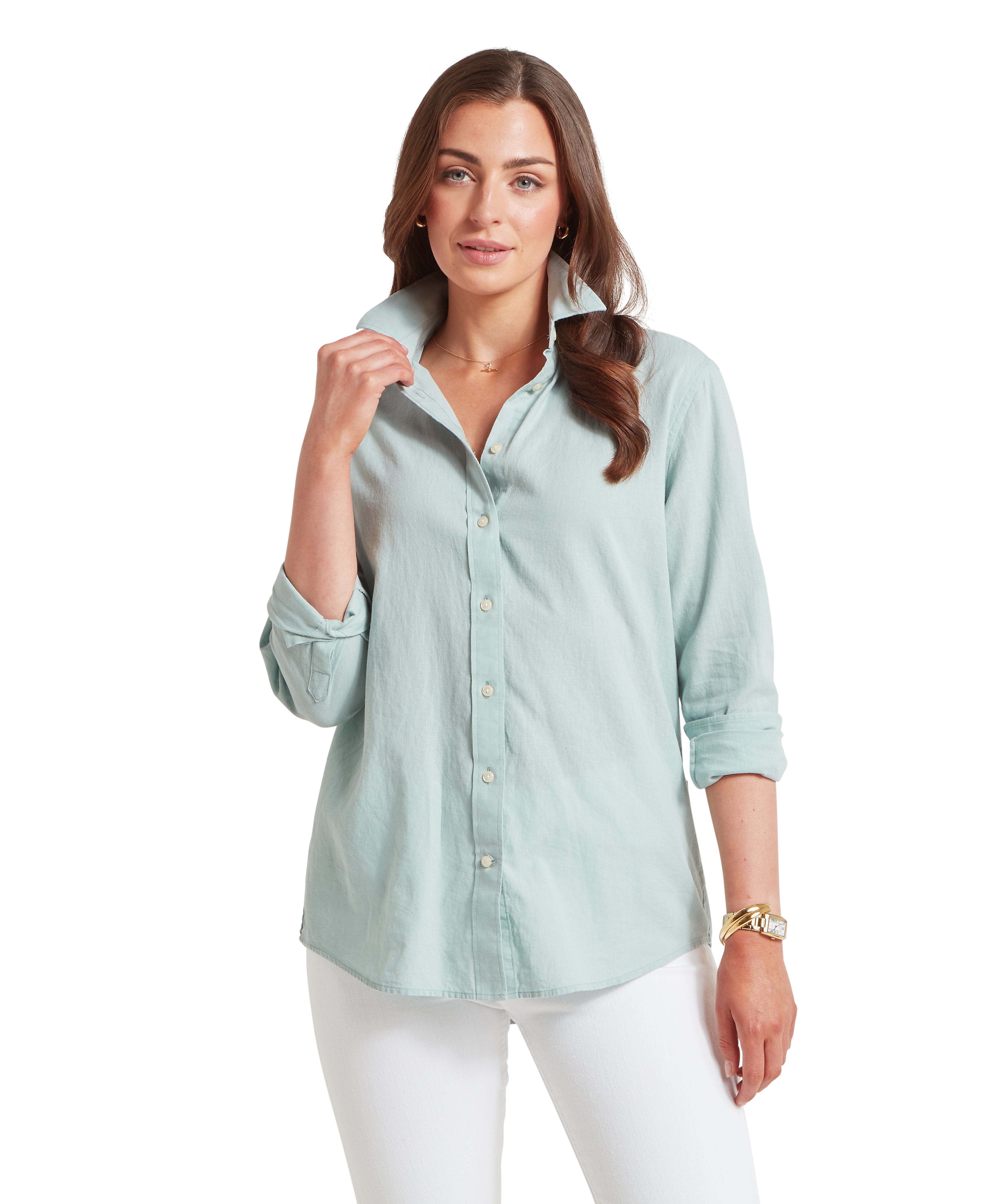 Woman wearing a light blue button-up shirt and white trousers on a white background