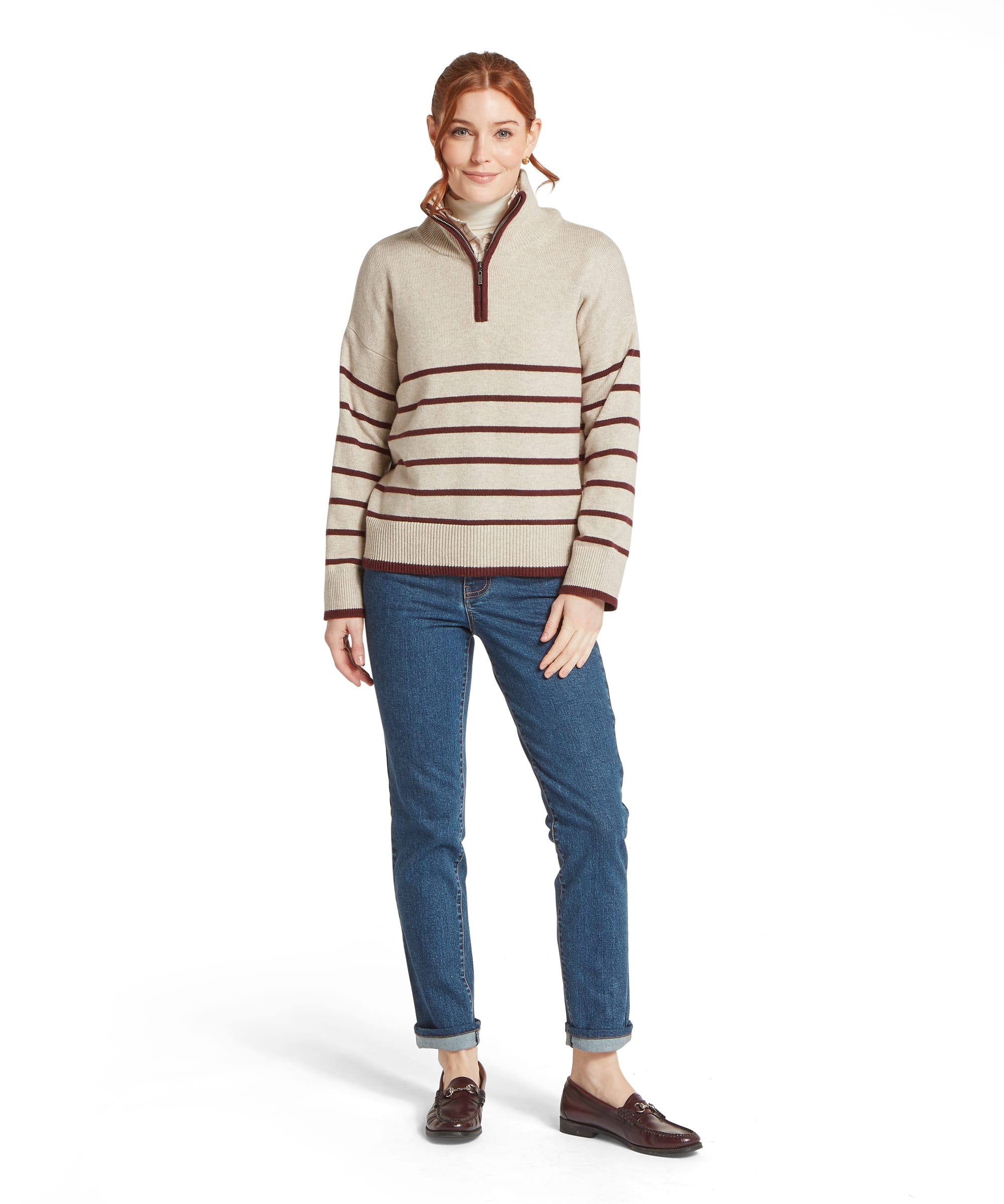 Full-length view of the Schöffel Women's Sandsend 1/4 Zip Knit Jumper in Oatmeal with burgundy stripe, styled with straight-leg blue jeans and burgundy horsebit loafers, showing the relaxed boxy silhouette and contrast ribbed hem