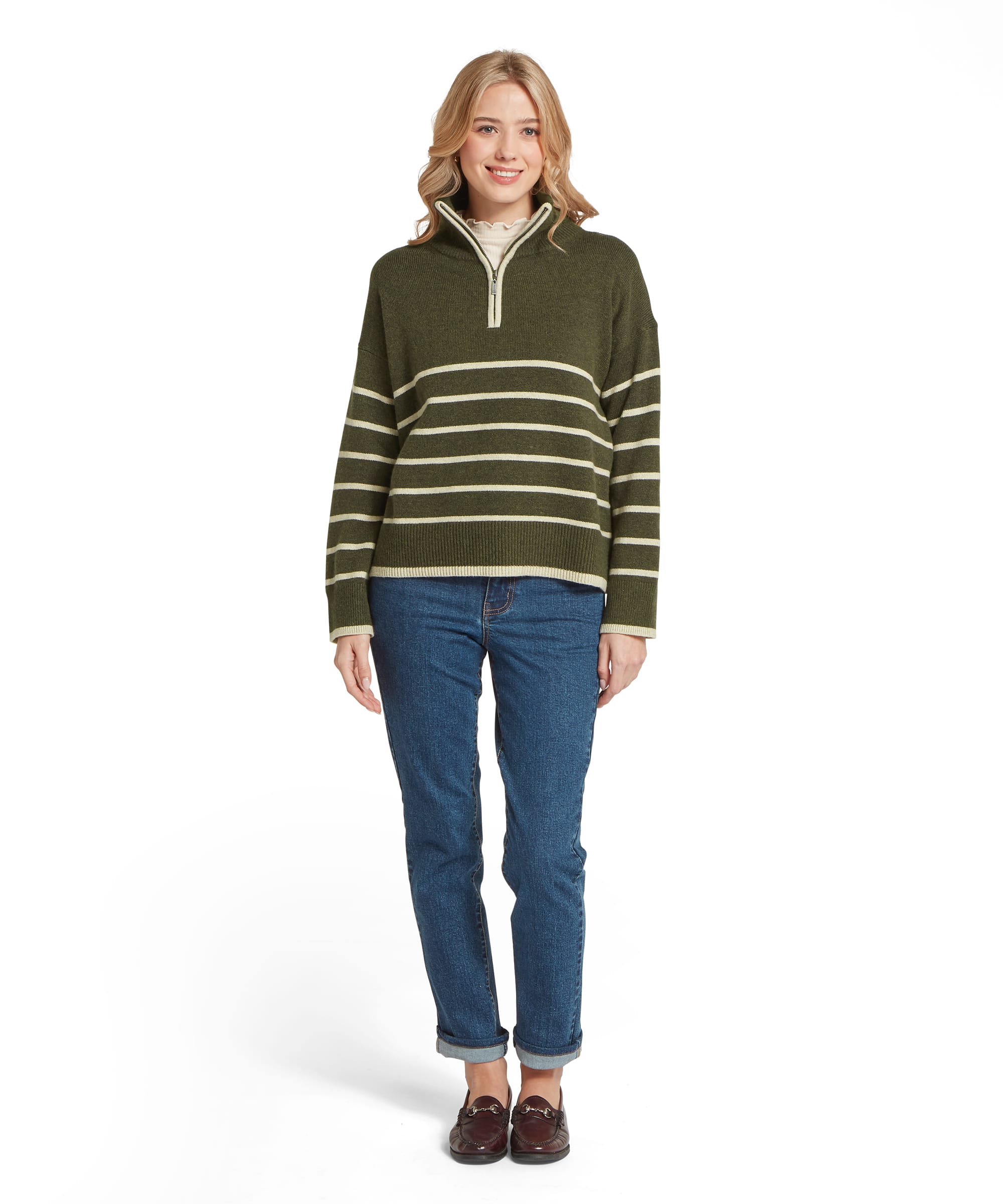 Full-length view of the Schöffel Women's Sandsend 1/4 Zip Knit Jumper in Khaki Green with cream stripe, worn with turn-up blue jeans and burgundy horsebit loafers, showcasing the relaxed country styling