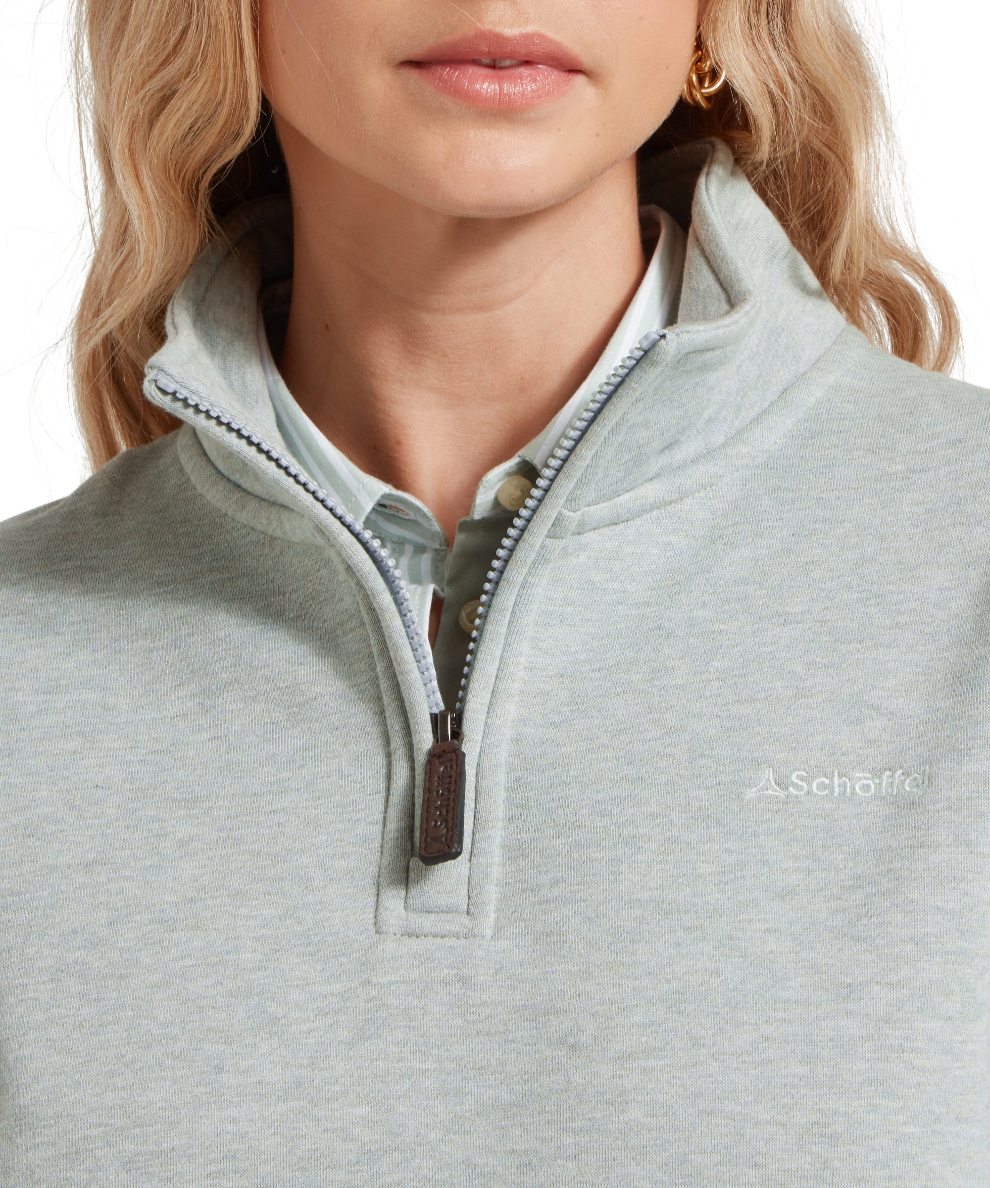 Close-up of the chest area of the Schöffel Sennen Cove Sweatshirt for Women in Light Blue, highlighting the embroidered brand logo and zipper details.