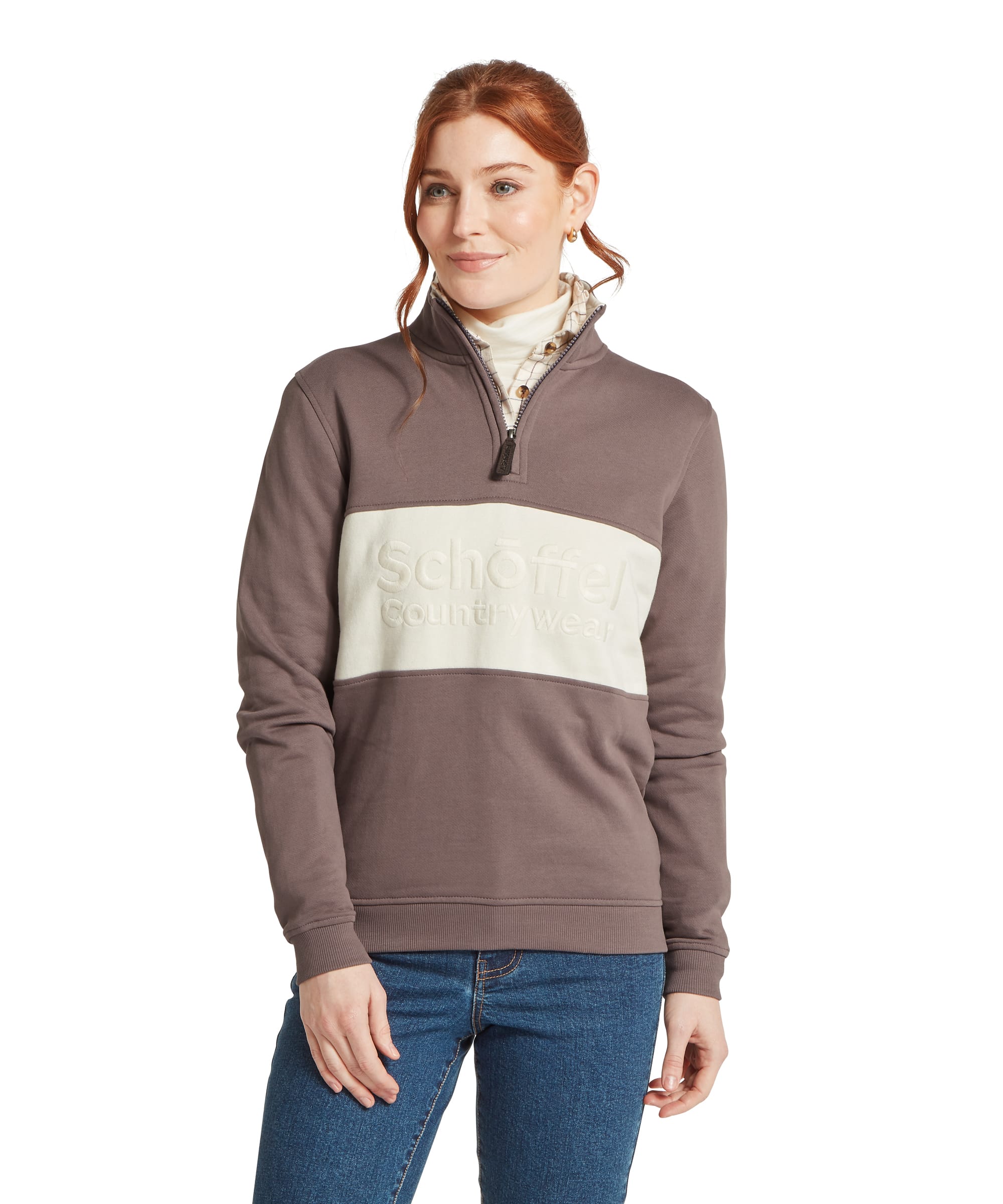Schöffel Women's St Agnes Sweatshirt in warm taupe brown, front view showing colourblock design with cream chest panel and raised Schöffel Countrywear logo, quarter-zip funnel neck, worn over a windowpane-check shirt and cream roll-neck with blue jeans