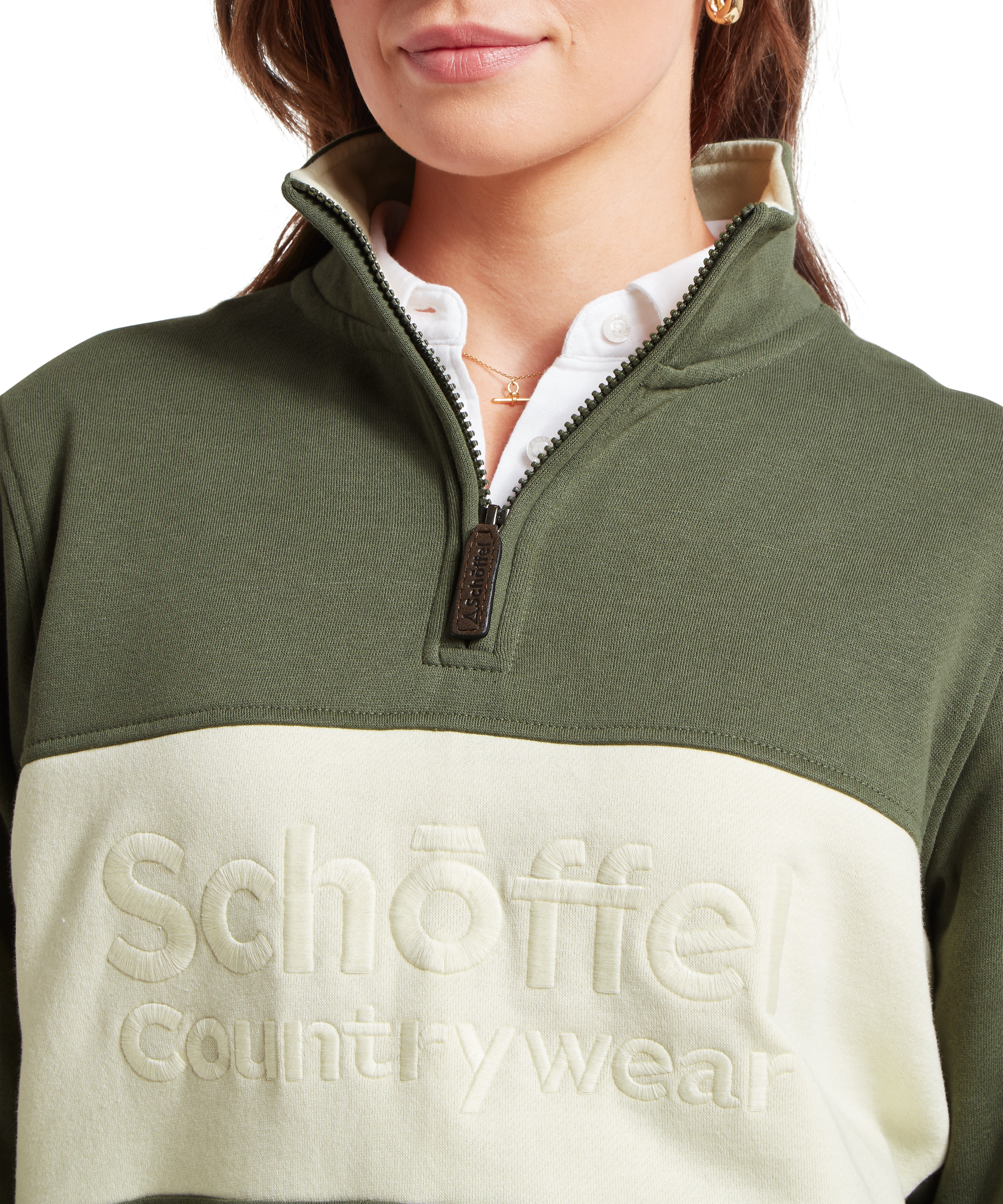 Close-up of a woman wearing a green and cream quarter zip sweatshirt with 'Schoffel Country Wear' branding.