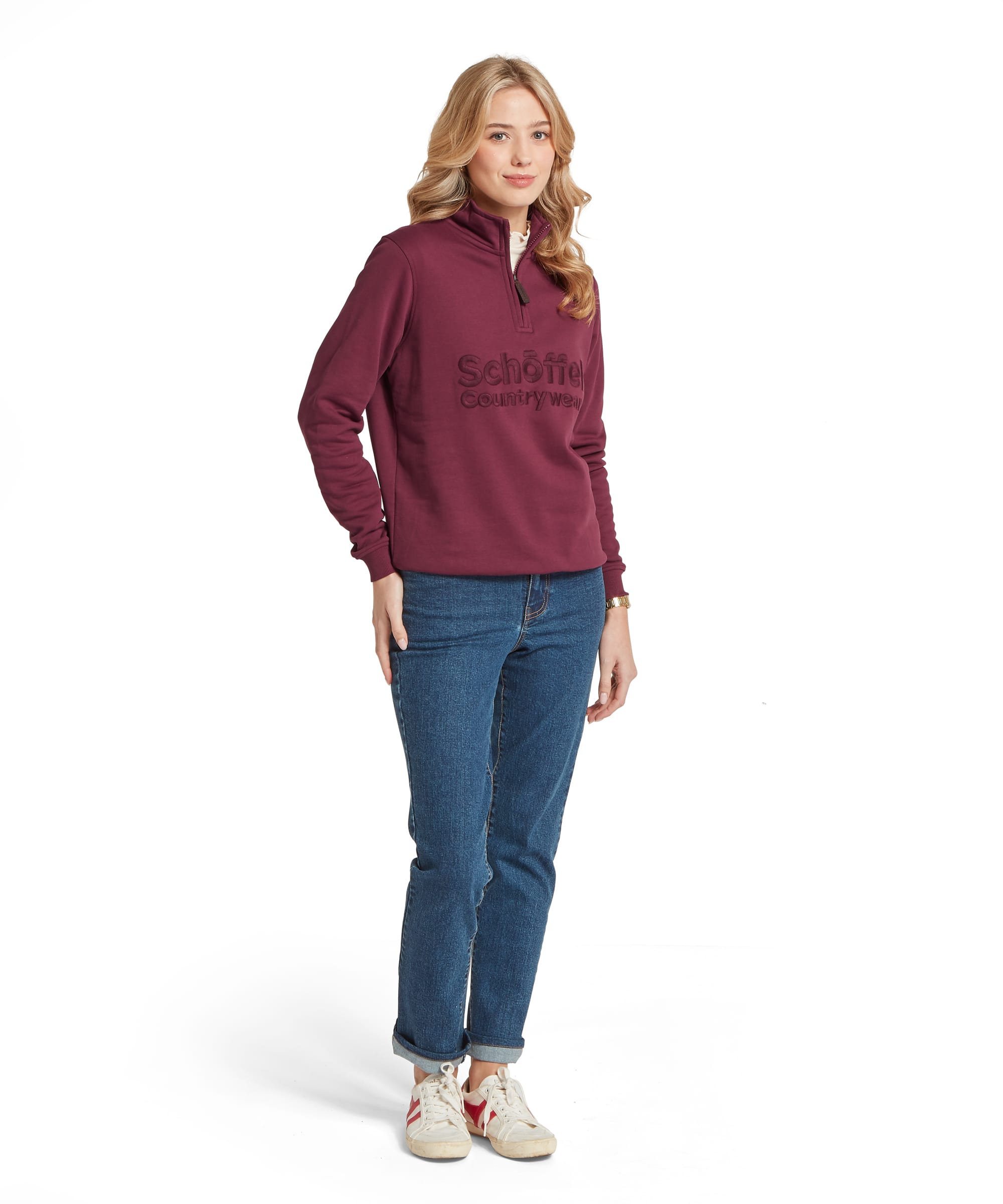 Schöffel Women's St Issey Sweatshirt in deep burgundy red, full-length front view with quarter-zip funnel neck and tonal raised Schöffel Countrywear embossed logo on chest, styled with a cream frill-neck base layer and blue straight-leg jeans with trainers