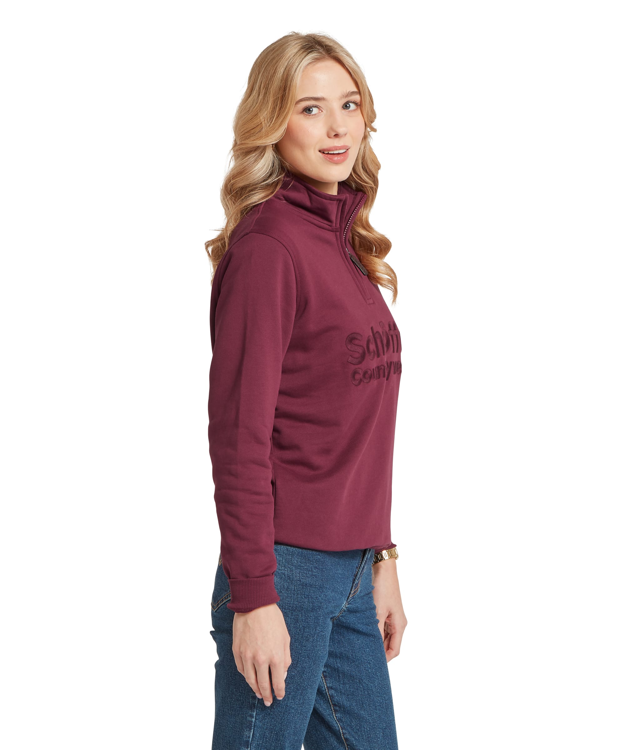 Schöffel Women's St Issey Sweatshirt in deep burgundy red, side view showing the quarter-zip funnel neck, tonal embossed Schöffel Countrywear logo on chest, ribbed cuffs, and elasticated ribbed hem, worn with blue jeans