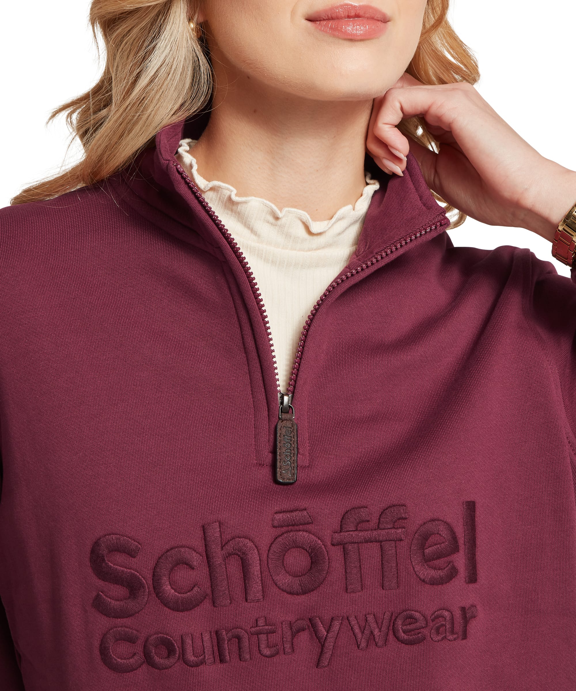 Close-up of the Schöffel Women's St Issey Sweatshirt in burgundy red, showing the quarter-zip funnel neck with Schöffel branded zip pull, tonal embossed Schöffel Countrywear logo lettering on chest, and cream frill-neck layer underneath