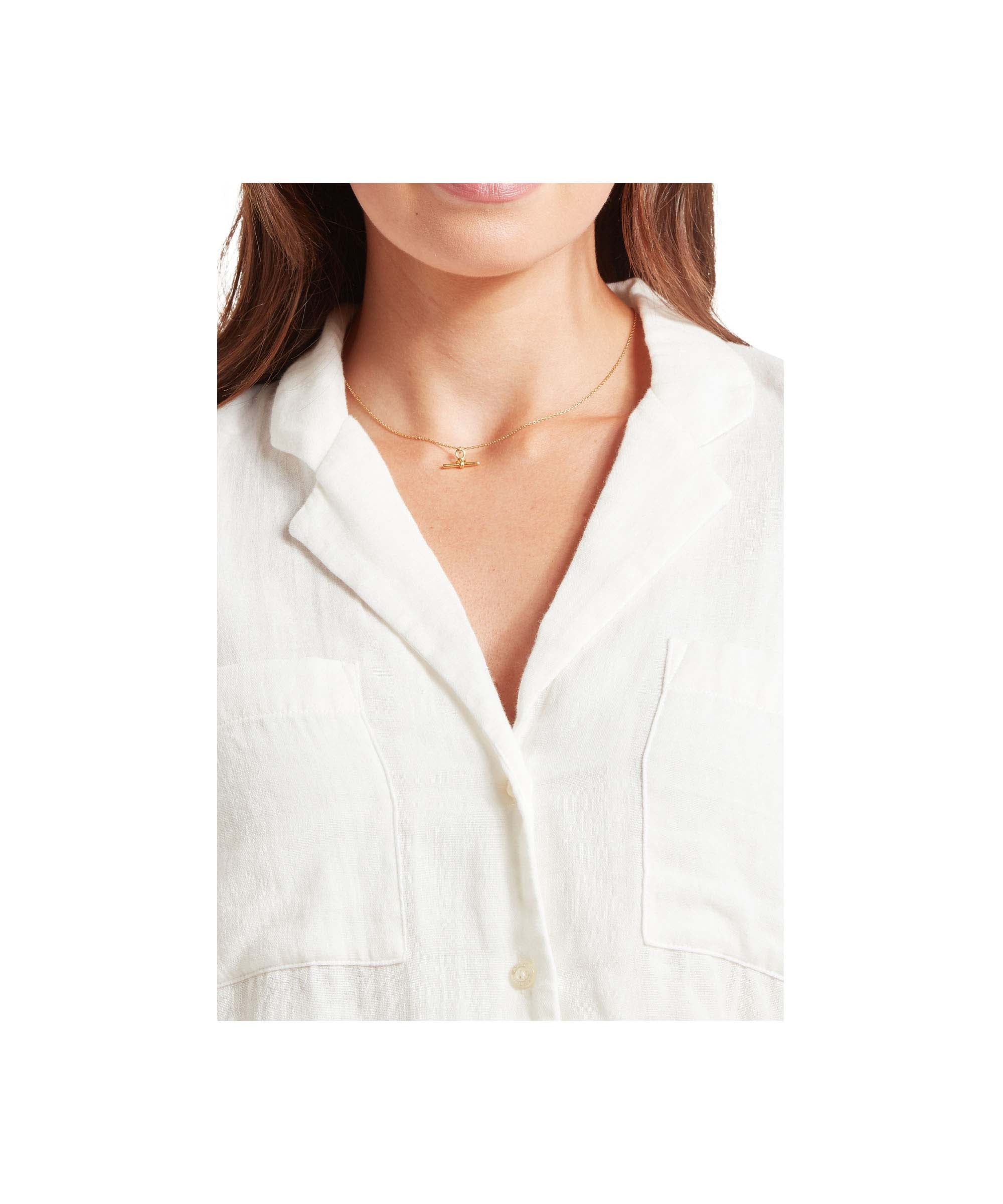 Close-up of a person wearing a white shirt with a necklace on a white background