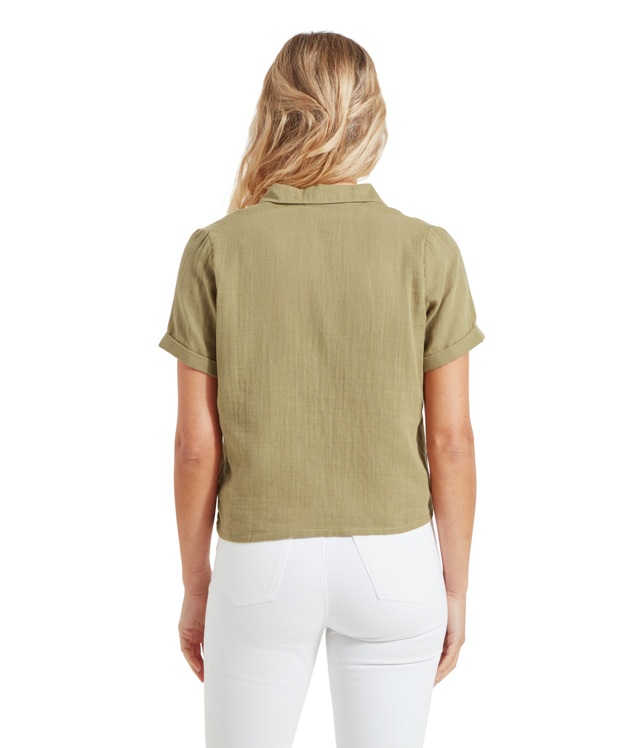 The back view of the Schöffel Summerfield Shirt for Women in Green shows the model standing straight. The shirt fits loosely and has a comfortable, casual style. She pairs it with white jeans, and her blonde hair cascades down her back.