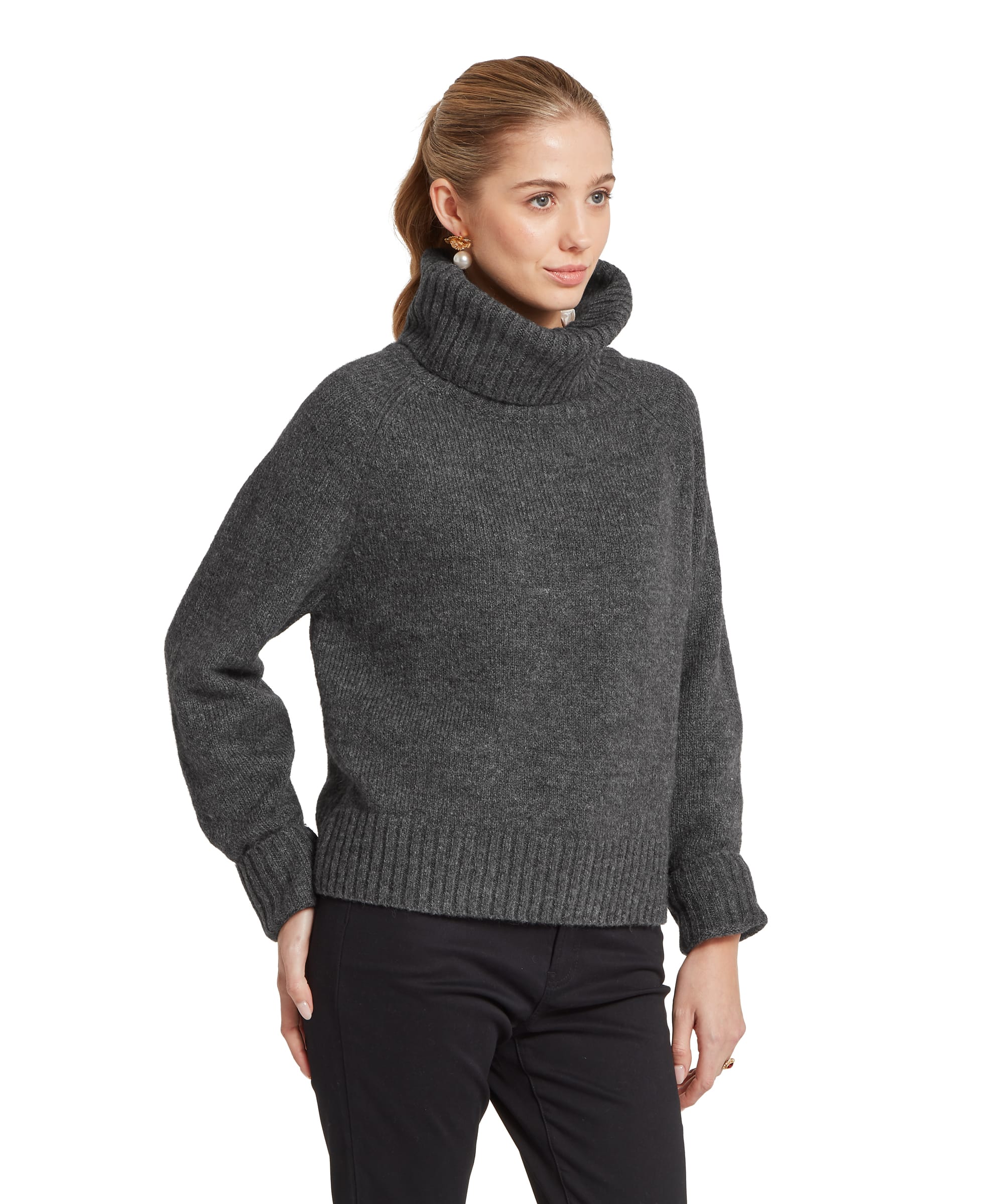 Three-quarter view of the Women's Schöffel Sutton Roll Neck Jumper in charcoal grey, an oversized knit with a generous cowl neck, deep ribbed hem and wide raglan sleeves, styled with slim black trousers and a pearl floral drop earring.
