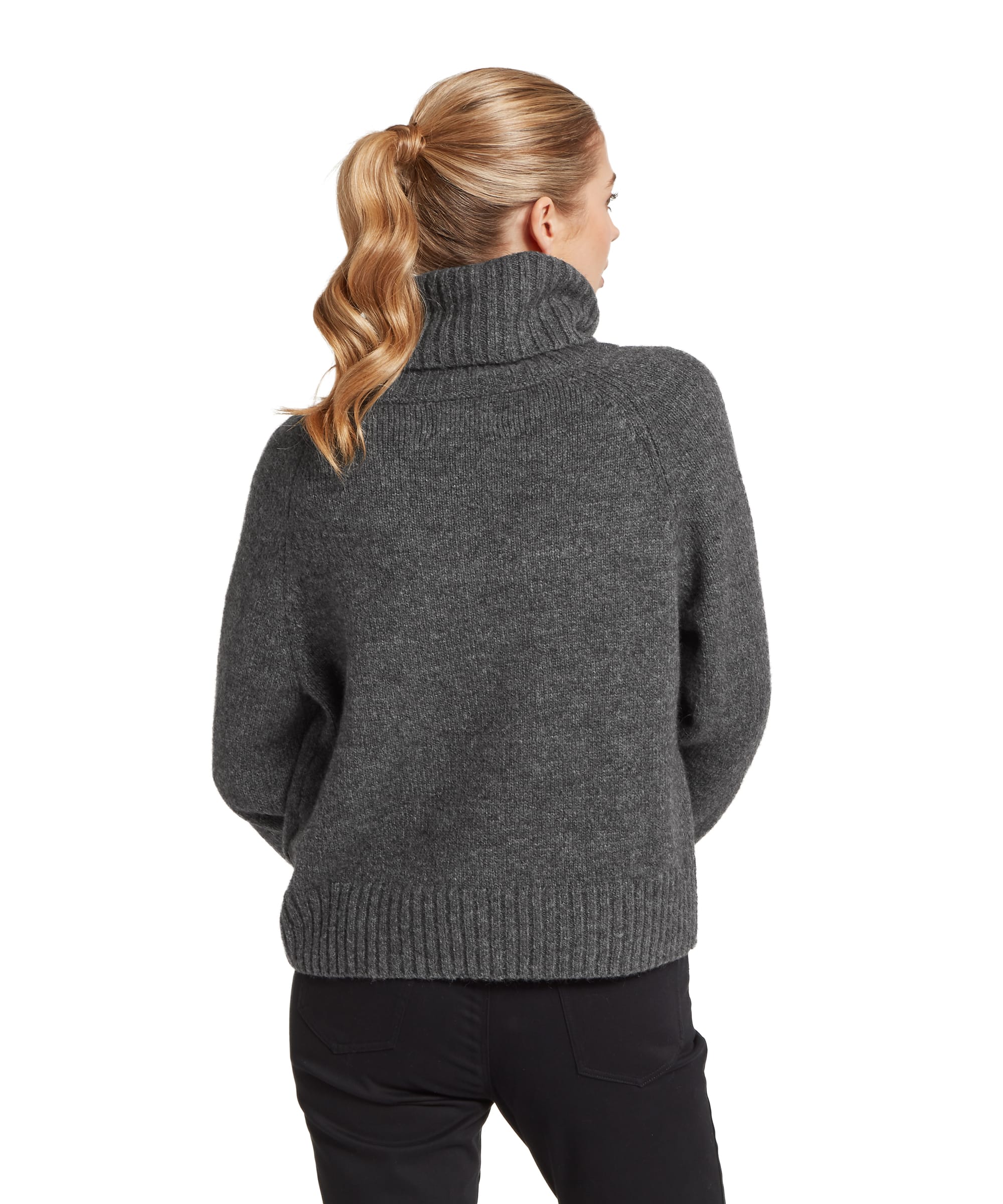 Rear view of the Women's Schöffel Sutton Roll Neck Jumper in charcoal grey, showing the relaxed oversized knit silhouette, deep ribbed hem and cuffs, and generous roll neck, paired with slim black trousers.