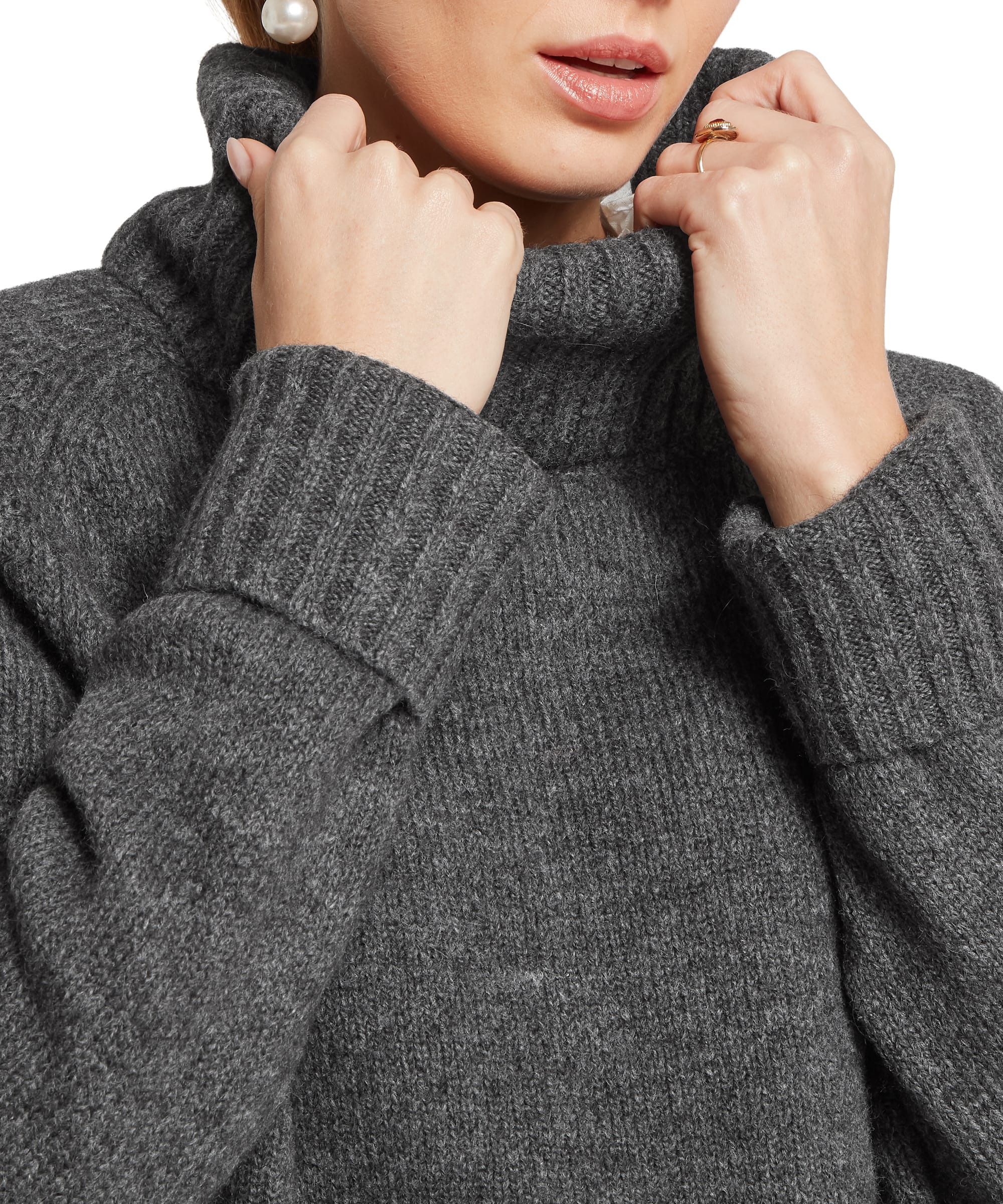 Close-up detail of the Women's Schöffel Sutton Roll Neck Jumper in charcoal grey, showing the generous ribbed roll neck being pulled up, showcasing the soft, chunky knit texture and wide ribbed cuffs.