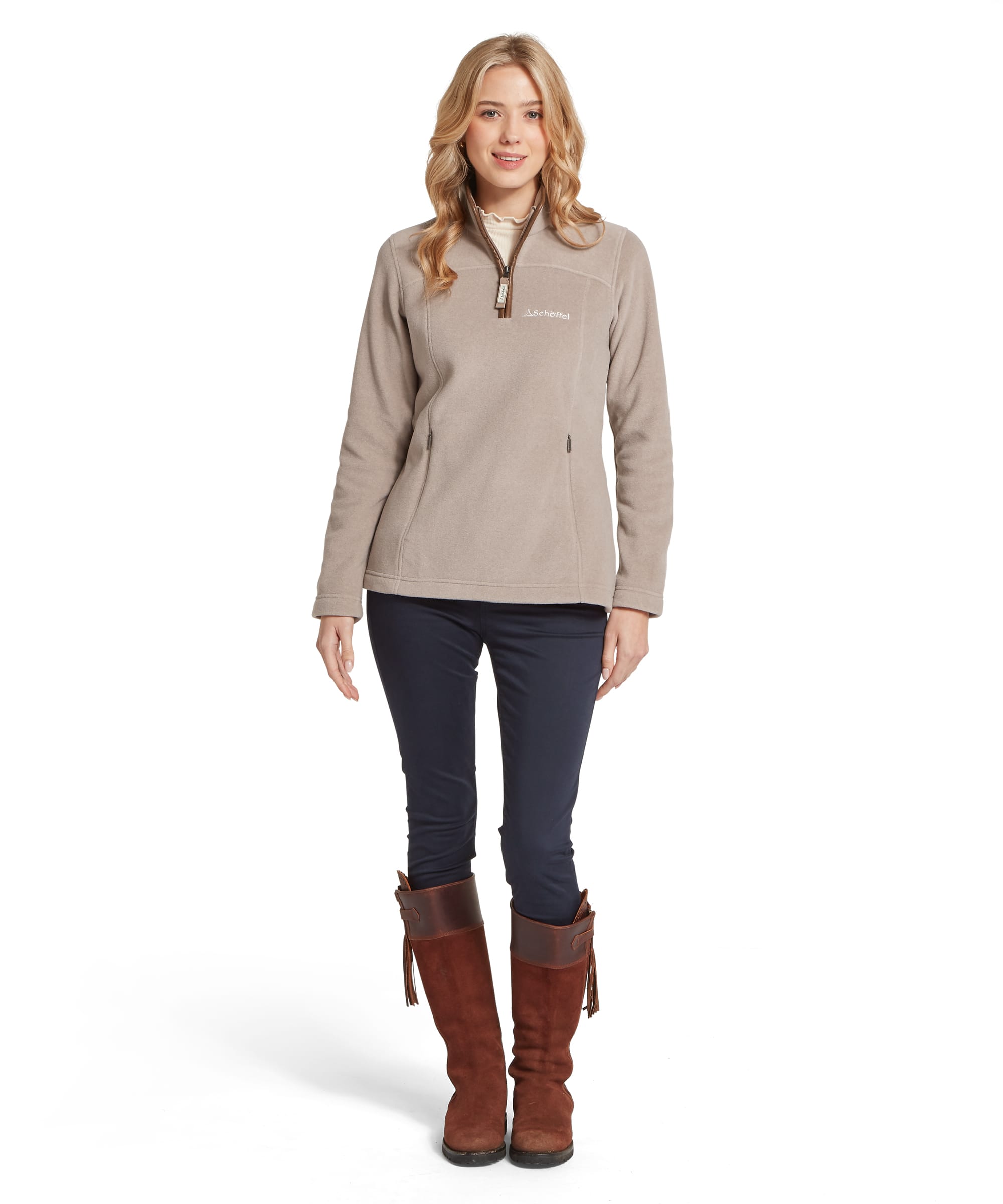 Schöffel Women's Tilton II 1/4 Zip Fleece in warm stone beige, full-length front view with Schöffel logo, zip pockets and frill-collar base layer, worn with navy riding trousers and tan leather long boots