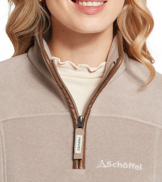 Schöffel Tilton II women's 1/4 zip fleece in beige, close-up of quarter-zip collar with contrast brown trim and embroidered logo, worn over ruffled knit top