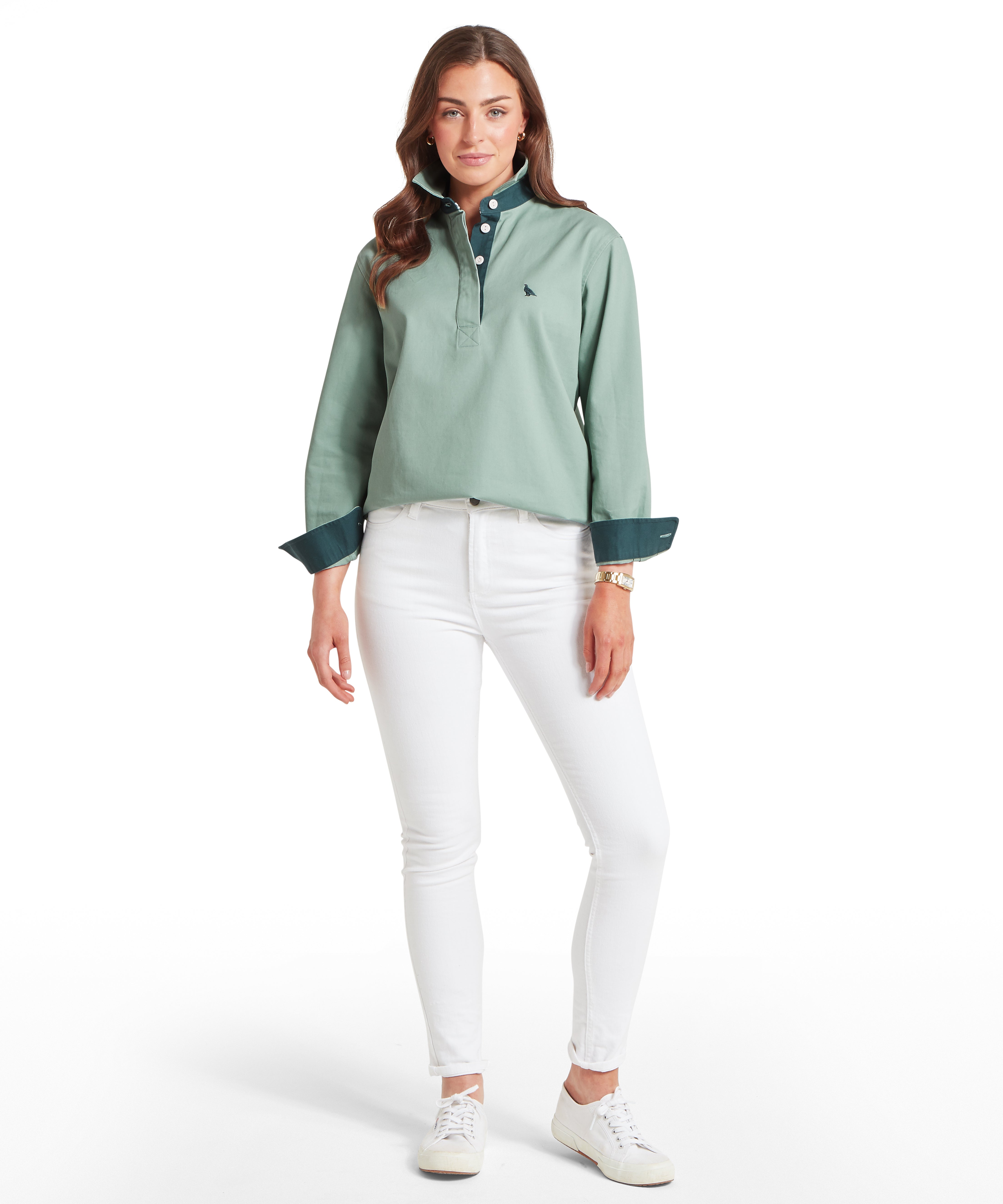 Woman wearing a green deck shirt and white jeans against a white background
