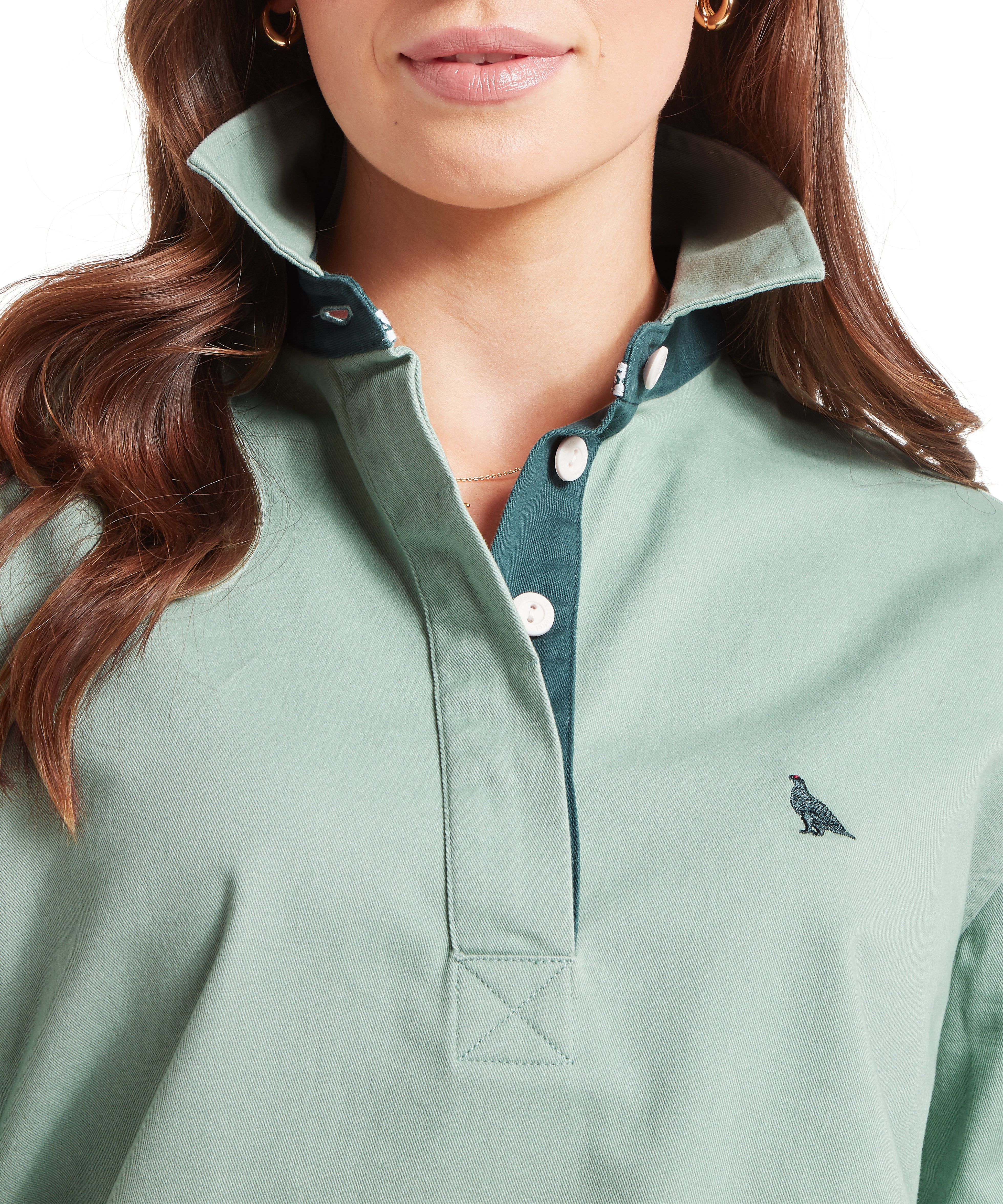 Close-up of a woman wearing a green deck shirt.  Her collar is pulled up showing a dark green accent underneath the collar.