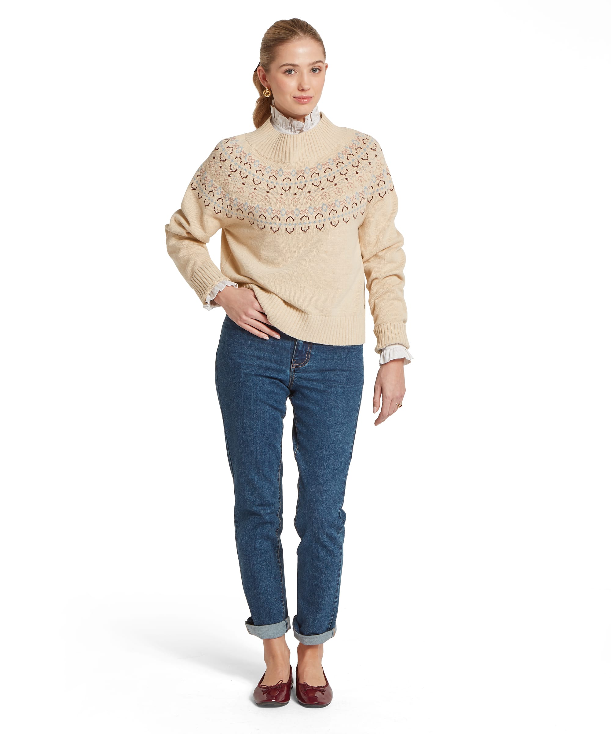 Full-length view of the Women's Schöffel Tresness Fair Isle Jumper in oatmeal cream, showing the relaxed fit with Fair Isle yoke pattern in cornflower blue, dusky pink and chocolate brown, ribbed mock neck and hem, layered over a white frill-collar shirt with relaxed blue denim jeans with turn-ups and burgundy bow ballet flats.